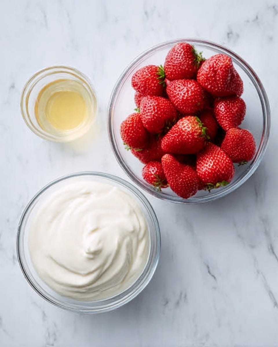 The image shows two clear glass bowls on a white marbled surface; the bowl on the right is filled with whole red strawberries, vibrant and fresh-looking, while the bowl on the left contains a smooth, white creamy substance with soft peaks. Next to the bowls, there is a small clear glass with a light yellow liquid inside. The scene is bright and clean, focusing on the contrasting colors and textures of the strawberries, cream, and liquid. Photo taken with an iphone --ar 4:5 --v 7