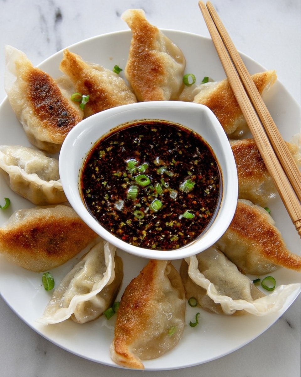 The image shows a white plate with eight golden brown dumplings arranged in a circle around a small white bowl filled with dark brown dipping sauce. The sauce is textured and has small bright green chopped scallions sprinkled on top. The dumplings have a crispy, pan-fried texture on one side and a soft, steamed texture on the other. To the right of the plate, there is a pair of light wooden chopsticks resting beside the bowl. The plate is set on a white marbled surface. photo taken with an iphone --ar 4:5 --v 7