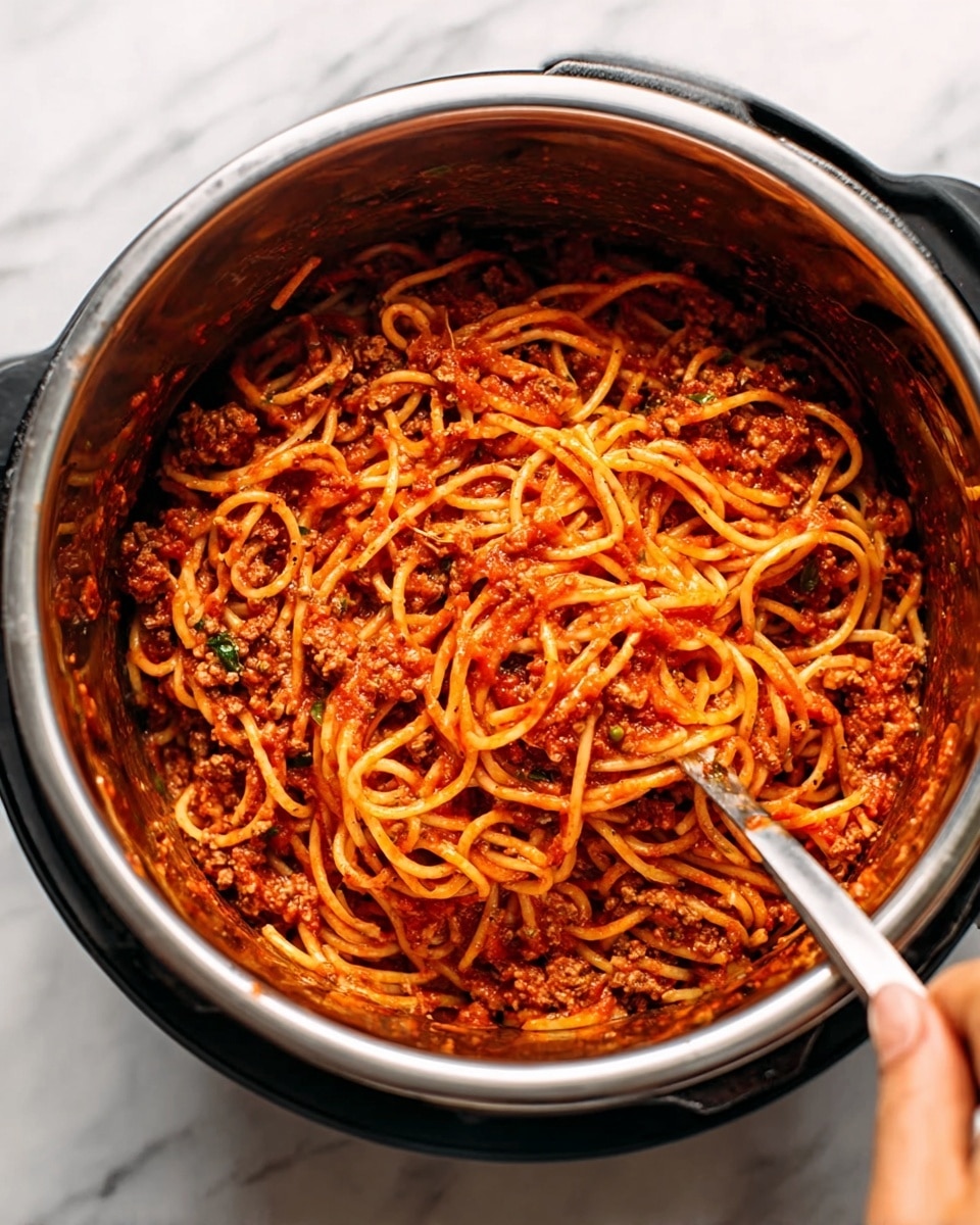 The image shows a close-up view of a pot filled with cooked spaghetti mixed with rich red tomato sauce. The spaghetti noodles are long and slightly twisted, coated well with a thick, chunky red sauce containing bits of ground meat and herbs. Inside the pot, there is a silver utensil mixing the pasta, with a woman's hand holding it. The surface beneath the pot is a white marbled texture. photo taken with an iphone --ar 4:5 --v 7