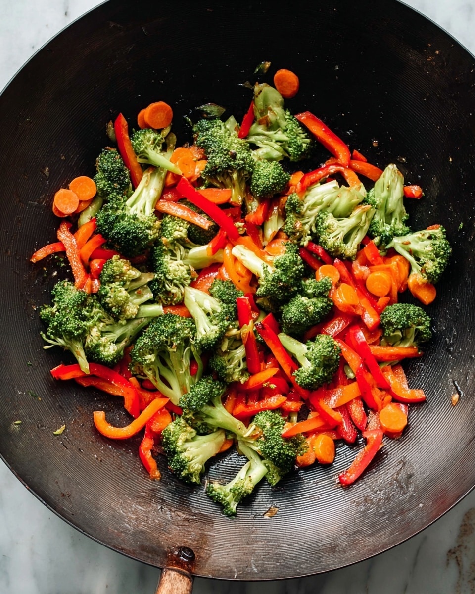 Inside a large black wok, bright green broccoli florets are mixed with thin strips of red bell pepper and round slices of orange carrot. The vegetables look lightly cooked with shiny surfaces and some browning spots. The broccoli pieces are scattered unevenly and layered with the red pepper strips and carrot circles on top and underneath, creating a colorful mix. The wok sits on a surface with a white marbled texture. photo taken with an iphone --ar 4:5 --v 7