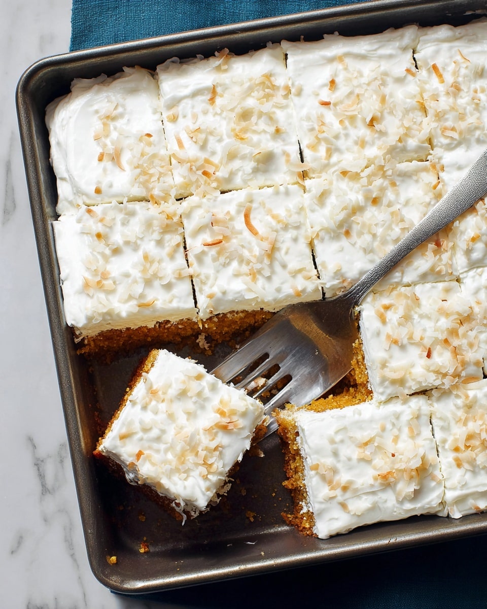 A metal baking tray holds a square cake cut into smaller squares, with one piece lifted by a fork. The cake has two layers: the bottom is a golden-brown crumbly crust, and the top is a thick, smooth white frosting sprinkled with light toasted coconut flakes. The tray rests on a white marbled surface. photo taken with an iphone --ar 4:5 --v 7