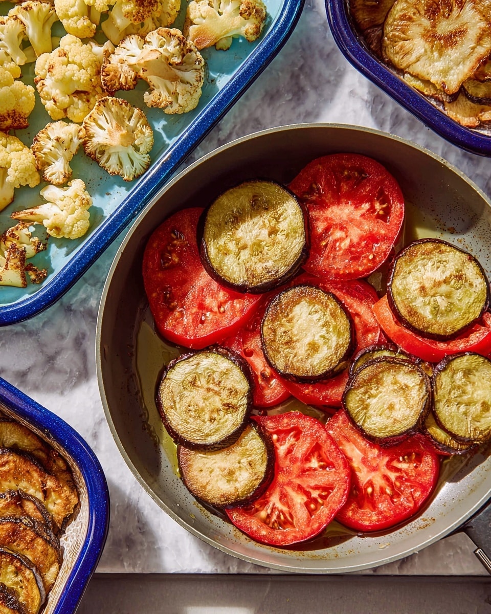 The image shows a gray pan with two layers of vegetables inside. The bottom layer has bright red tomato slices spread evenly. On top, there is a layer of lightly browned round eggplant slices placed covering most of the tomato slices. Next to the pan, on a white marbled surface, two blue trays hold more roasted vegetables; one tray has golden-brown cauliflower pieces, and the other has more browned eggplant slices. Photo taken with an iphone --ar 4:5 --v 7